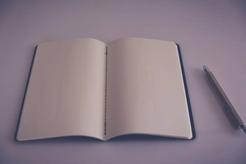 Open notebook on a blank page with a pen beside it