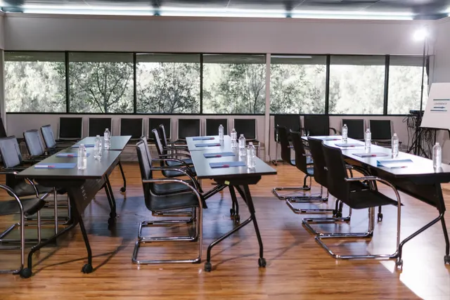 Salle de réunion vide, tables disposées en U avant une session de travail