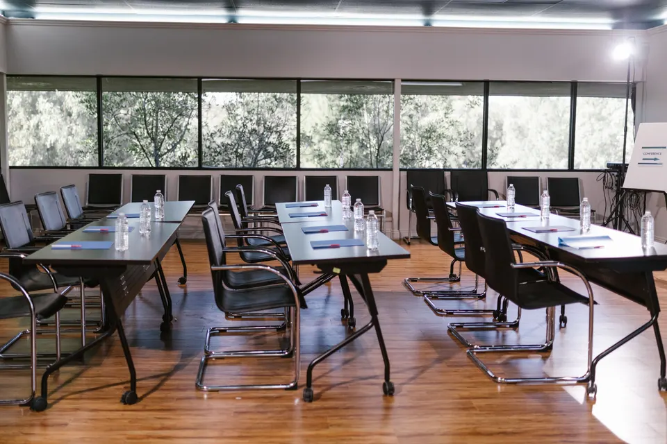 Salle de réunion vide, tables disposées en U avant une session de travail